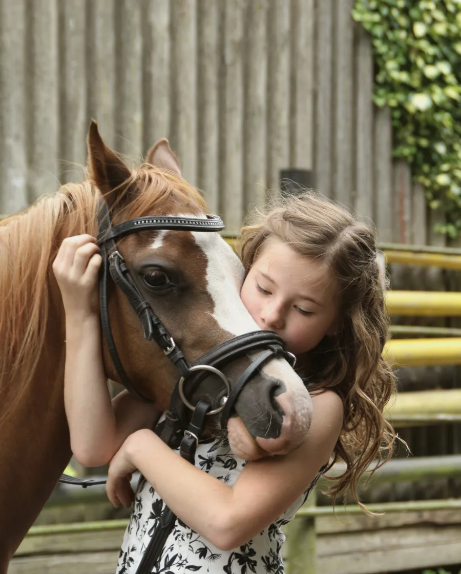 Une jeune cavalière serre son poney dans ses bras